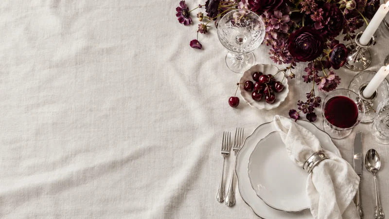 Original overhead table-setting artwork with ivory linen, plum flowers and elegant glassware